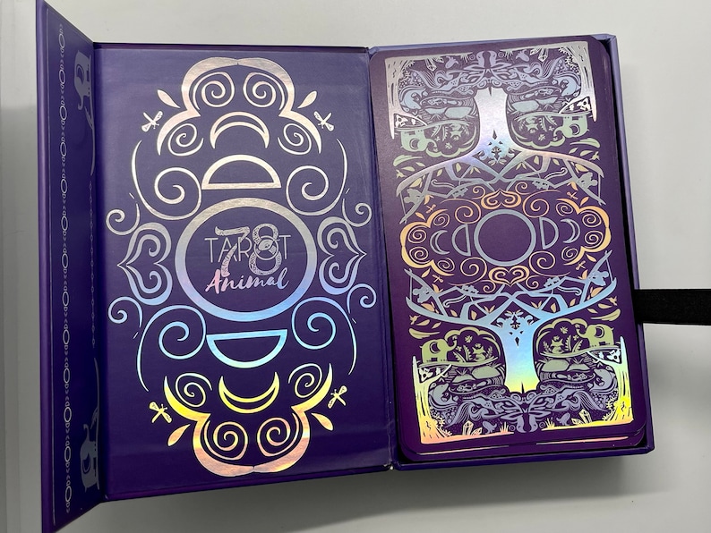 May include: A purple box with a holographic design featuring the text "78 Tarot Animal". The box is open to reveal a card with a holographic design of a tree with intricate details.