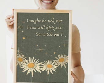 Op de afbeelding: Een rechthoekige ingelijste print met een donker olijfgroene achtergrond, witte madeliefjesillustraties aan de onderkant en gouden steraccenten. De tekst luidt: I might be sick but I can still kick ass. So watch out!