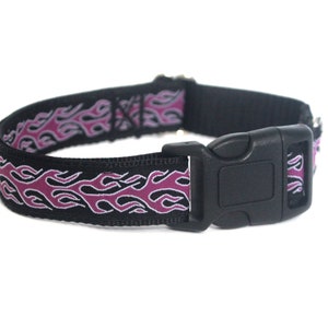 Puede incluir: Un collar de perro negro con un diseño de llamas rosa y blanco.