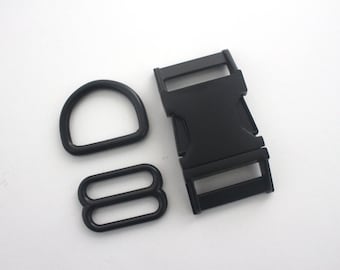 May include: A collection of black hardware components, comprising a D-ring, a tri-glide slide, and a side-release buckle. These are commonly used in crafting and sewing, suitable for bags, straps, and other accessories.