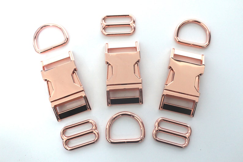 May include: Rose gold metal hardware set, including D-rings, slide adjusters, and side-release buckles. The set is ideal for crafting dog collars, leashes, and other pet accessories. The hardware has a shiny finish.