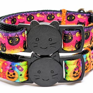 May include: Two pet collars featuring black cat-shaped plastic buckles. The top collar has a purple, pink, and orange gradient pattern with black cat faces. The bottom collar has a rainbow gradient pattern with orange jack-o'-lantern faces.
