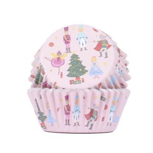 May include: Pink cupcake liners with a Nutcracker themed design. The liners feature a Christmas tree, a ballerina, and a Nutcracker soldier.