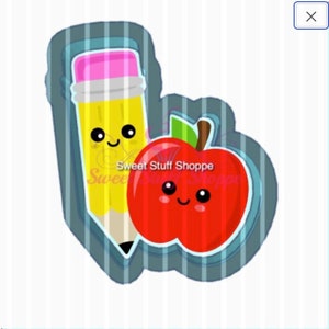 May include: A red apple and a yellow pencil with a pink eraser, both with smiling faces, are cut out of blue cookie dough. The text "Sweet Stuff Shoppe" is visible in the background.