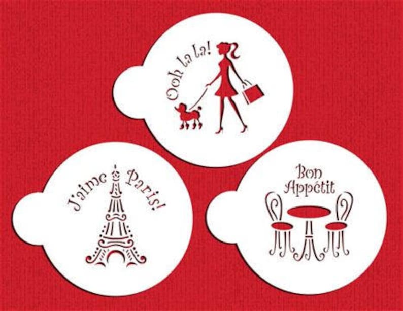May include: Set of three white plastic stencils with Parisian-themed designs. The stencils feature a woman walking a poodle with the text "Ooh la la!" a table and chairs with the text "Bon Appetit", and the Eiffel Tower with the text "J'aime Paris!"