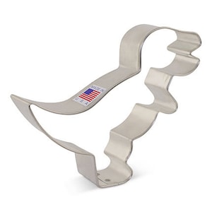 May include: A shiny, silver-colored metal cookie cutter in the shape of a duck. The cutter has a curved body, a beak, and a tail. A small sticker with the American flag and the words "MADE IN USA" is visible.