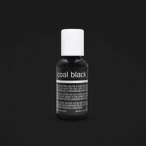 May include: A small, black bottle with a white cap, labeled "coal black." The bottle contains a dark liquid, and the label includes ingredient information. The background is a solid black.