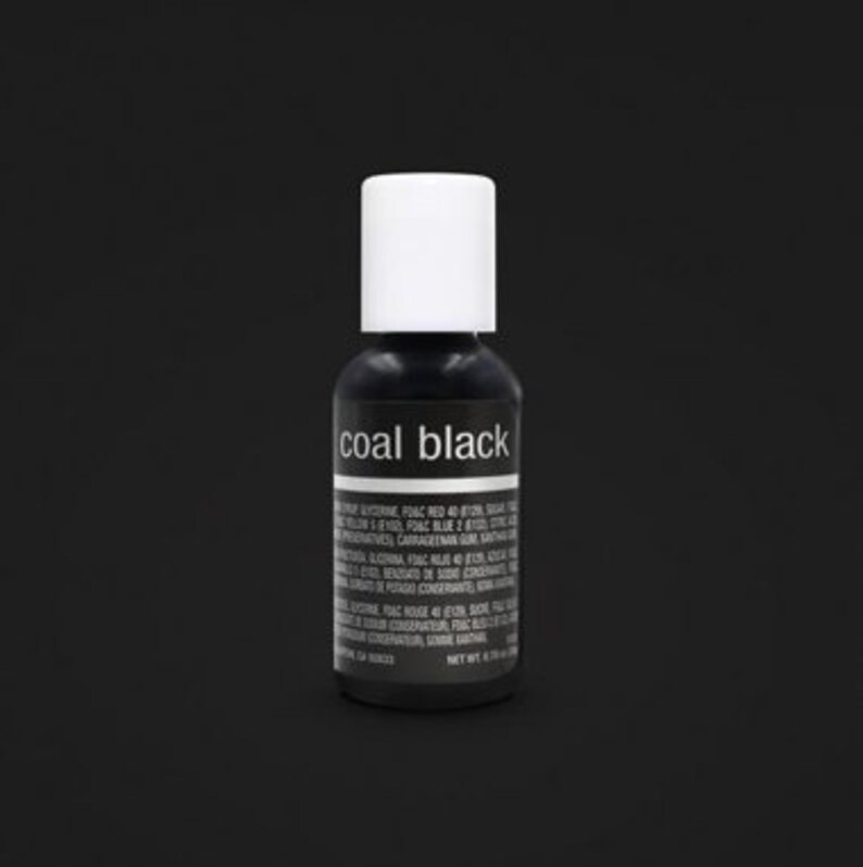 May include: A small, black bottle with a white cap, labelled "coal black." The bottle contains a dark liquid, and the label includes ingredient information. The background is a solid black.