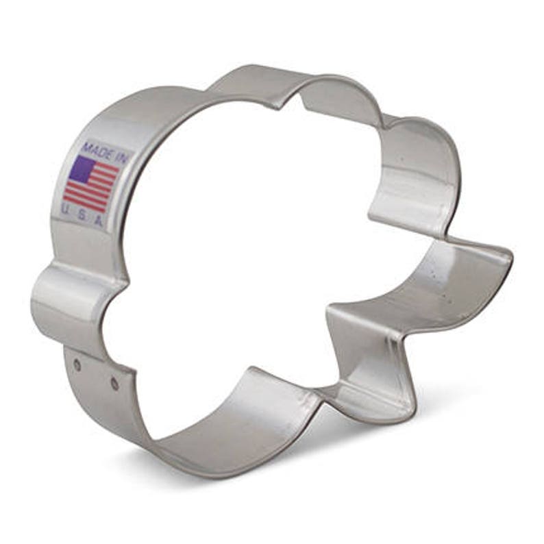 Puede incluir: Un cortador de galletas de metal plateado con forma de nube y borde festoneado. El cortador tiene "Made in USA" impreso en el lateral.