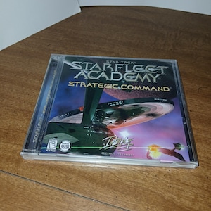 May include: A Star Trek: Starfleet Academy Strategic Command PC game in a clear plastic case. The cover art features a spaceship and the game's title. The game is rated E for Everyone.