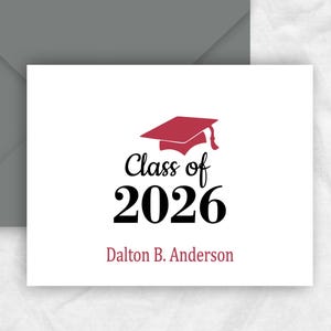 May include: A white folded note card with a crimson graduation cap graphic and the text "Class of 2026." The name "Dalton B. Anderson" is printed below the year. A charcoal gray envelope is behind the card. The text "FOLDED NOTE CARDS - BLANK INSIDE" is at the bottom.