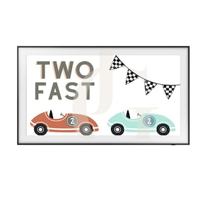Könnte beinhalten: Ein gerahmter Druck mit dem Text "TWO FAST" in Schwarzweiß. Zwei Spielzeug-Rennwagen, einer rot und einer blau, fahren aufeinander zu. Ein schwarz-weißes kariertes Flaggenbanner hängt über den Autos.