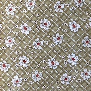 May include: A brown fabric with a repeating pattern of white flowers with red centers. The flowers are arranged in a diamond pattern on a grid of thin brown lines.