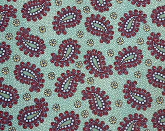 May include: Close-up of a fabric with a repeating paisley pattern. The paisley shapes are primarily burgundy with white and green accents, set against a light green background dotted with small white circles and yellow flower shapes.