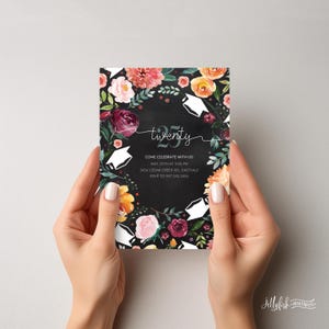 May include: Graduation party invitation with a black background and a floral wreath with white graduation caps. The text reads "twenty" and includes the date, time, address, and RSVP information.