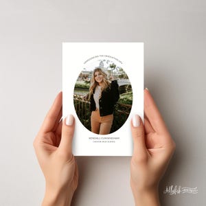 May include: A white graduation announcement card with a black oval border. The oval contains a photo of a young woman in a black jacket and brown pants. The text "Announcing the Graduation of..." is at the top of the card. The text "Kendall Cunningham, Canyon High School" is at the bottom of the card.