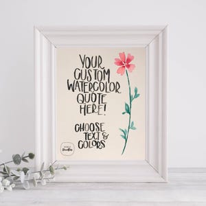 May include: A framed print with a watercolor flower and text. The text reads "YOUR CUSTOM WATERCOLOR QUOTE HERE! CHOOSE TEXT & COLORS." The flower is pink with a green stem and leaves. The frame is white.