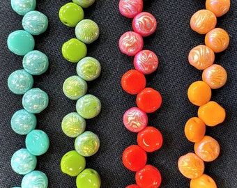 May include: Rows of colorful beads in shades of teal, lime green, red, and orange. Some beads have a swirled pattern, while others are solid. The beads are arranged on a black background, creating a vibrant display.