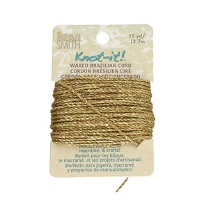 May include: Gold-colored waxed cord, 15 yards long, for macrame and crafts. The label reads "Knot-it! Waxed Brazilian Cord".