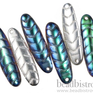 May include: Assortment of six iridescent glass beads with a chevron pattern. The beads are oval shaped and have a blue, green, and silver color.