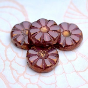 May include: Four iridescent glass flower-shaped beads in shades of pink and brown. The beads have a raised design and a metallic sheen.