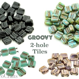 May include: A collection of 2-hole glass tiles in black, turquoise, and bronze with a grooved texture and gold accents. The tiles are labeled "GROOVY 2-hole Tiles".