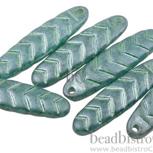 May include: Six teal green glass beads with a chevron pattern and a hole at each end. The beads are oval shaped and have a slightly textured surface.