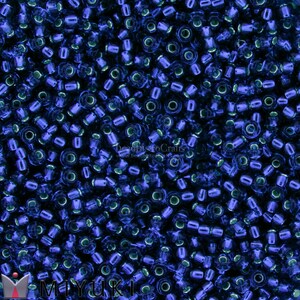 May include: A close-up image of a large quantity of small, round, blue glass beads. The beads have a metallic sheen and are arranged in a random pattern.