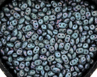 May include: A heart-shaped box filled with teal blue glass seed beads. The beads have a slightly iridescent finish and are shaped like a teardrop with two holes.