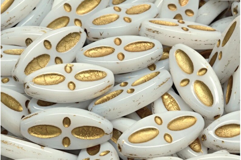 Peut inclure: Un groupe de perles ovales en verre blanc avec des accents dor&eacute;s. Les perles ont un aspect vieilli et sont parfaites pour la fabrication de bijoux.