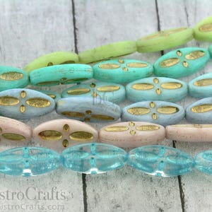 Peut inclure: Un brin de perles de verre ovales avec un motif de feuille d'or. Les perles sont dans des tons de bleu, vert et rose.