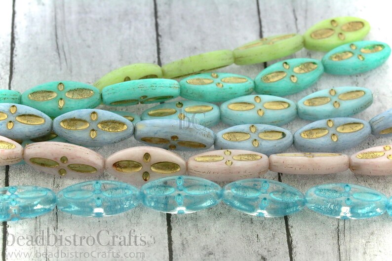 Peut inclure: Un brin de perles de verre ovales avec un motif de feuille d'or. Les perles sont dans des tons de bleu, vert et rose.