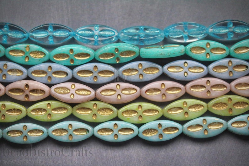 Peut inclure: Gros plan d'un brin de perles de verre ovales avec un motif dor&eacute;. Les perles sont dans des tons de bleu, vert et rose.