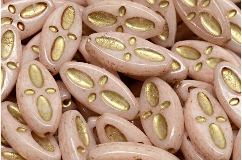 Peut inclure: Gros plan sur un groupe de perles en verre de forme ovale, de couleur rose clair et avec des accents dor&eacute;s. Les perles ont une surface textur&eacute;e et sont parfaites pour la fabrication de bijoux.