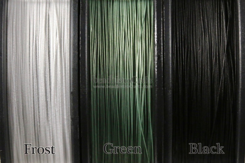 May include: Three spools of thread in different colors: frost, green, and black. The spools are labeled with the color names.