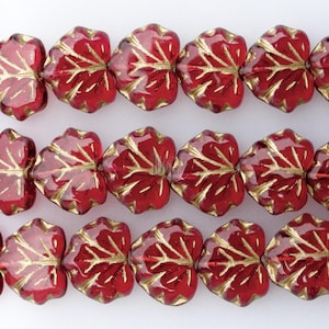 May include: A strand of red glass beads with gold leaf detailing in the shape of leaves.