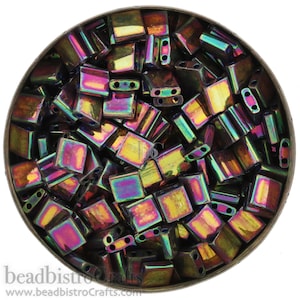 May include: A container filled with iridescent, square-shaped glass beads. The beads have a dark, metallic finish with shades of purple, green, and gold.
