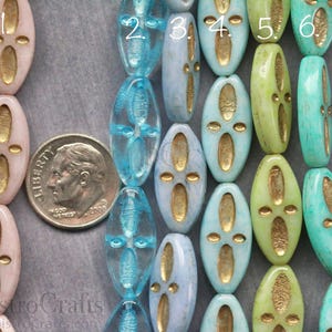 Peut inclure: Gros plan sur dix perles ovales en verre avec des accents dor&eacute;s. Les perles sont dispos&eacute;es en rang&eacute;e, avec les chiffres 2 &agrave; 6 visibles sur le dessus des perles. Les perles sont bleu clair, turquoise et vertes.