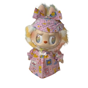May include: A whimsical doll with a large head, wearing a pink dress and hat adorned with postage stamp designs. The doll has a fluffy, multi-colored fur collar and a large bow on its head. The doll's eyes have a rainbow effect.