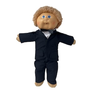 May include: A vintage doll with a round face, blue eyes, and light brown yarn hair. The doll is dressed in a black suit with a matching bow tie and pants. The doll's arms are outstretched.