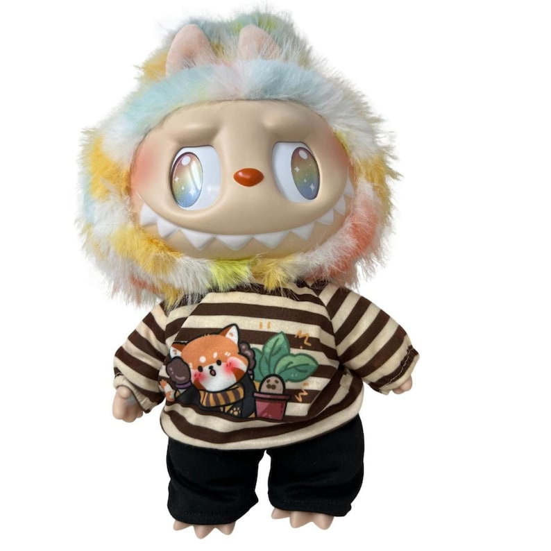 May include: A whimsical doll with a unique design. It features a smiling face with large, iridescent eyes and a multi-colored furry hood. The doll wears a striped brown and tan shirt with a red panda graphic and black pants.