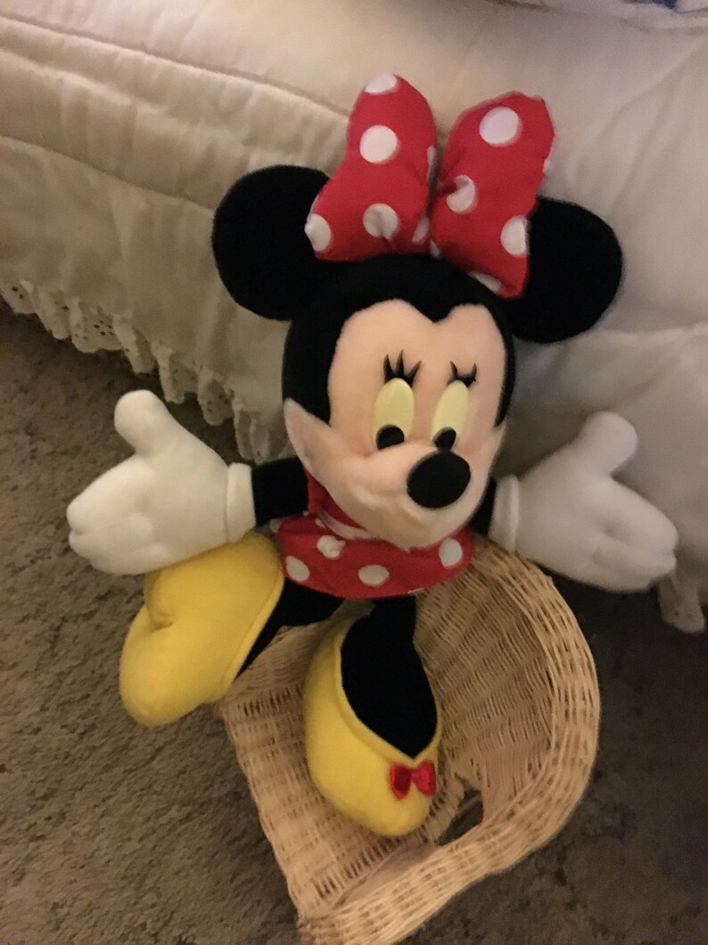 Peut inclure: Un jouet en peluche de Minnie Mouse portant un n&oelig;ud rouge &agrave; pois blancs et une robe rouge &agrave; pois blancs. Elle est assise dans un panier en osier.