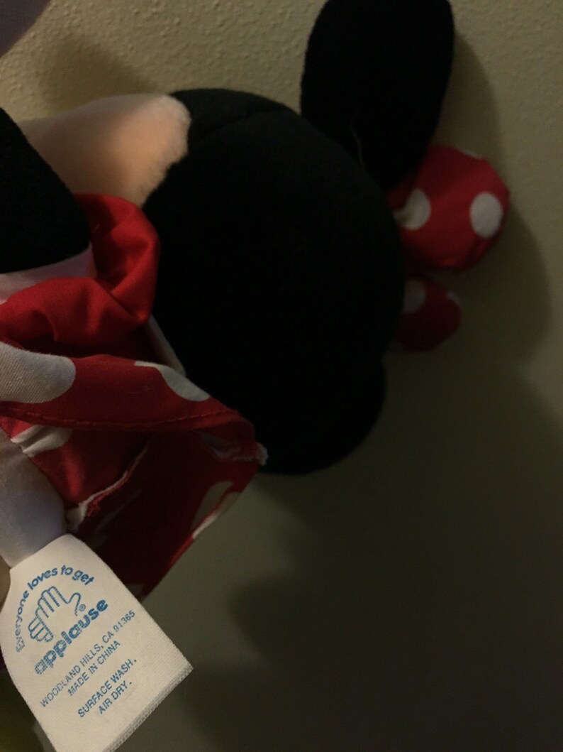 Peut inclure: Un jouet en peluche rouge et blanc &agrave; pois avec des oreilles noires et un visage blanc. Le jouet est &eacute;tiquet&eacute; "applause" et porte le texte "Everyone loves to get applause" sur l'&eacute;tiquette. L'&eacute;tiquette comprend &eacute;galement les informations "Woodland Hills, CA 91365, Made in China, Surface Wash, Air Dry."