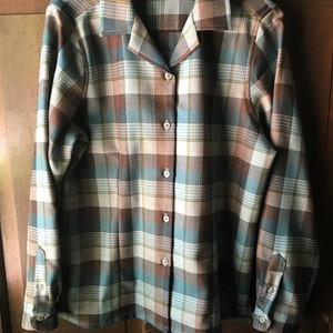 May include: A long-sleeved plaid shirt with a collared neckline and button closure. The shirt is brown, blue, and white with a plaid pattern. The shirt has a Pendleton label.