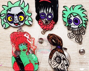 May include: Five colorful cartoon character badge reels. The characters are green, red, black, and brown. The characters are all different and have unique features. The badge reels are clear and have a silver retractable cord.