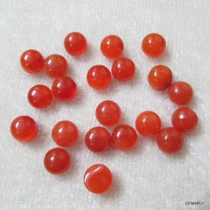 May include: A collection of 20 round, smooth, orange carnelian cabochons. The cabochons are approximately 10mm in diameter and have a polished finish.