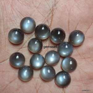 May include: A collection of 14 round, gray moonstone cabochons. The stones have a smooth, polished surface and a subtle shimmer.