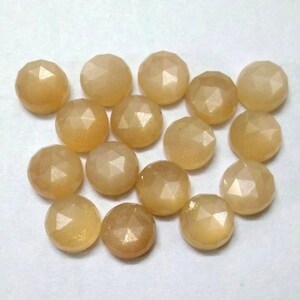 May include: A collection of 15 round, faceted, light brown gemstones. The stones have a shimmery, iridescent finish.