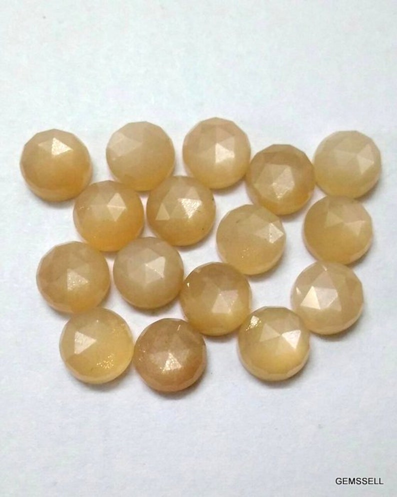 May include: A collection of 15 round, faceted, light brown gemstones. The stones have a shimmery, iridescent finish.