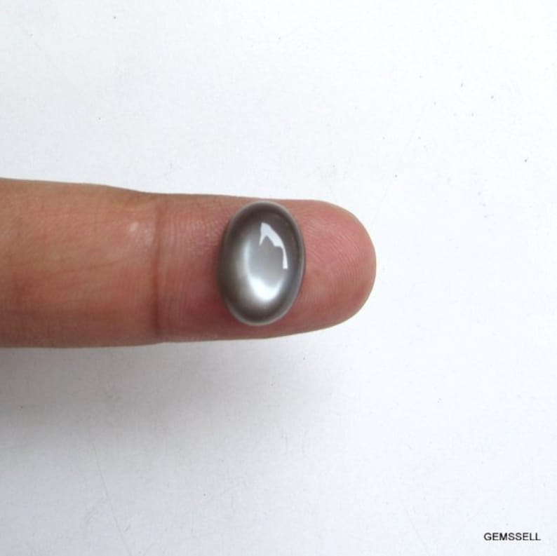 May include: A gray oval cabochon gemstone with a white iridescent sheen.